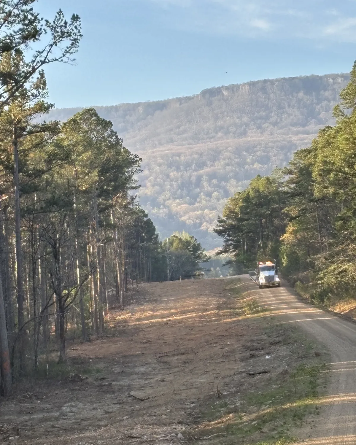 Truck on a dirt access road through wooded terrain
